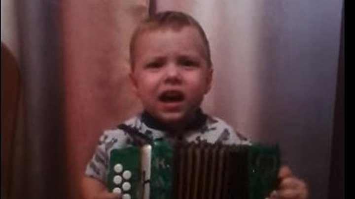 Забавный малыш играет на гармошке и поет